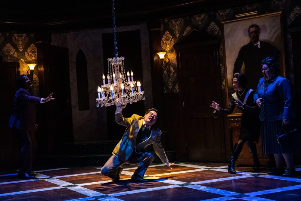 Photo of a person being comedically crushed by a chandelier while three others watch in horror.