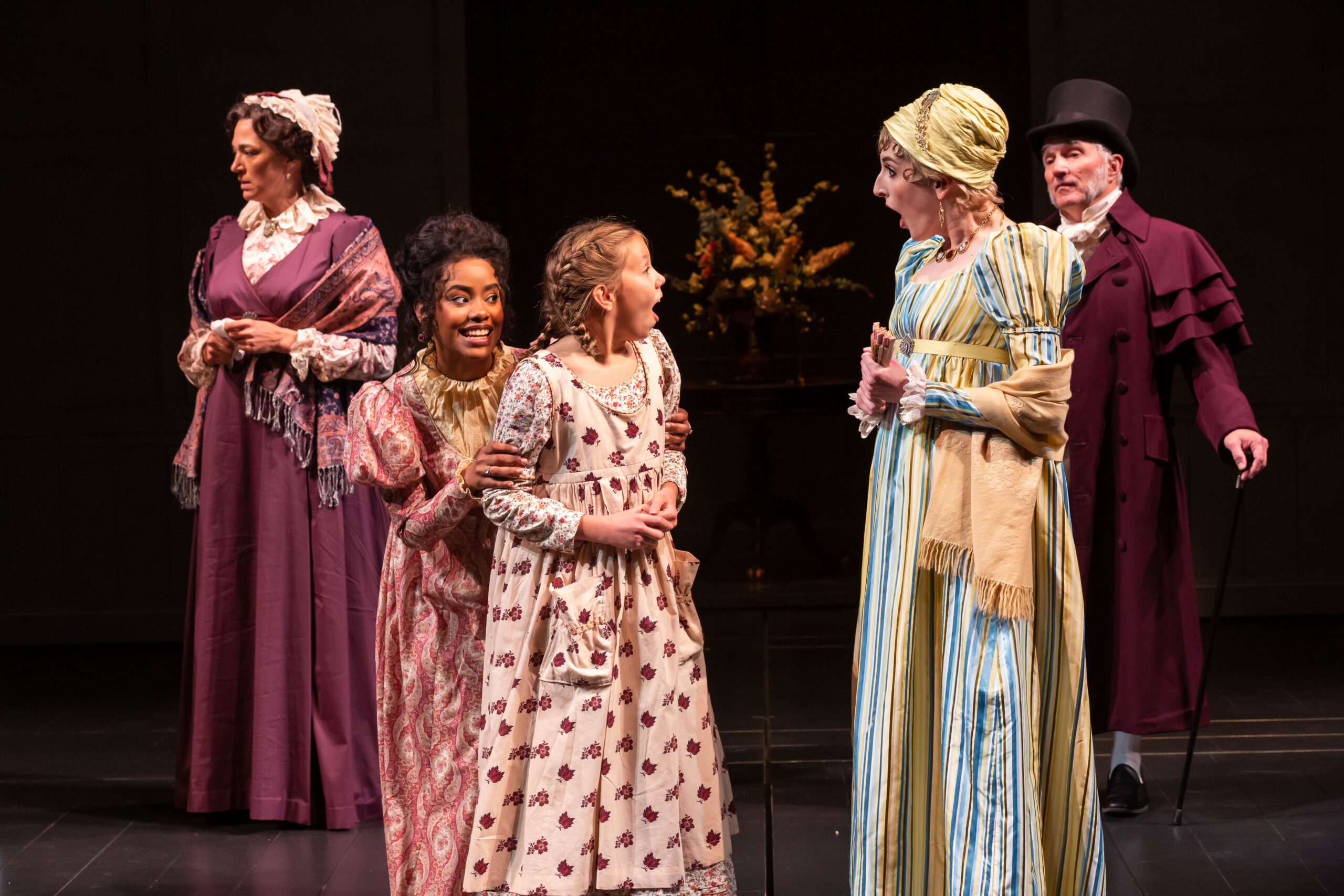 Photo of two adults and child in foreground talking, while two adults stand in background.