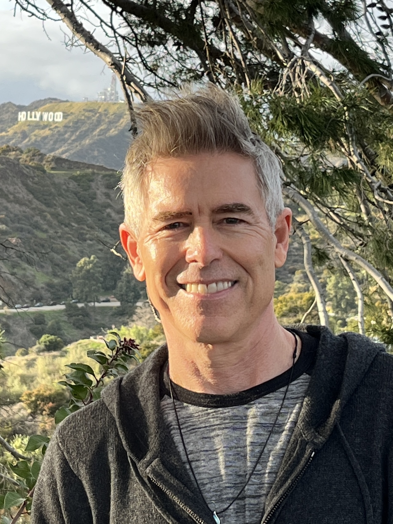 James Still smiling in front of the Hollywood Sign in Los Angeles